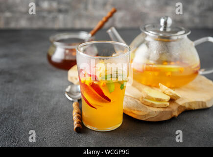 Glass cup of tea and teapot composition on grey background Stock Photo