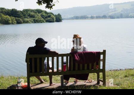 Couple sitting on bench overlooking Blagdon Lake Somerset Stock Photo