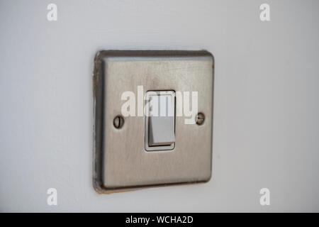 light switch, brushed chrome light switch on a white wall Stock Photo