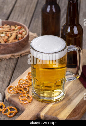 Glass mug of beer with snacks on a rustic wooden surface Stock Photo