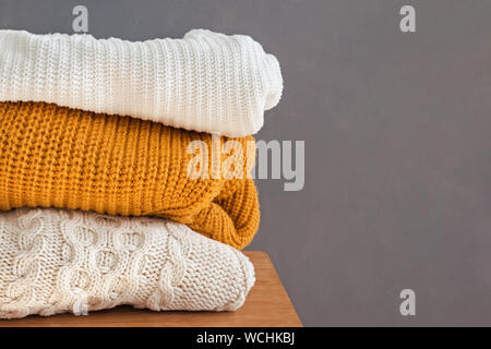 Stack of warm knitted sweaters on the chair close-up Stock Photo
