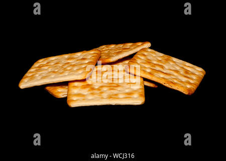 Stack of crispy crackers isolated against a black background. Stock Photo
