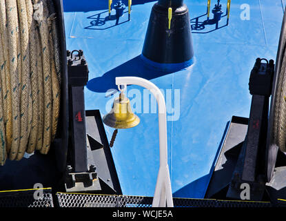 Gold colored bell on ship deck. Stock Photo