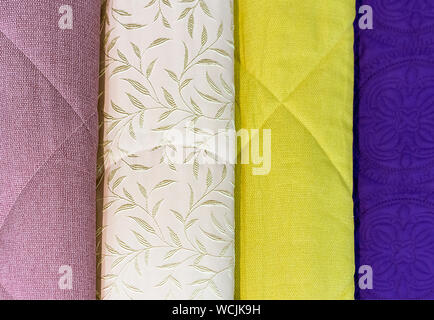 Bedspreads in different colors. Background from fabric of different colors. Stock Photo