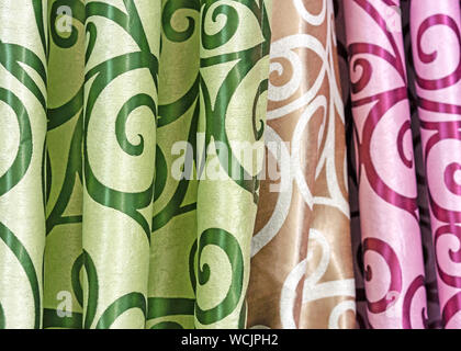 Multicolored curtain designs in a retail store window. Samples of the texture of multi-colored fabrics. Stock Photo