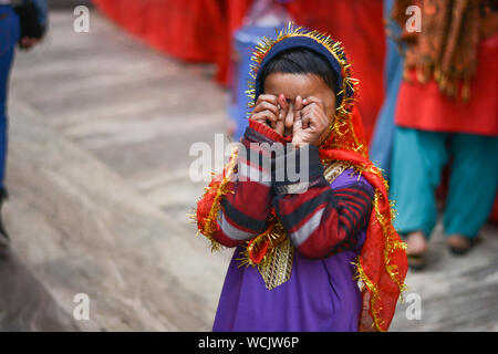 Girl child beggar giving expressions at camera in colorful religious dress. Stock Photo