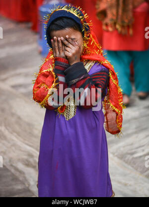 Girl child beggar giving expressions at camera in colorful religious dress. Stock Photo