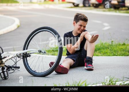 Teenage boy There is a elbow injury, as the bike falls while riding. Kid hurts his arm after falling off his bicycle. Child is learning to ride a bike Stock Photo