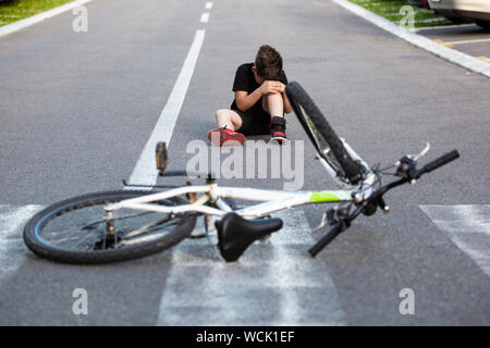 Teenage boy There is a knee injury, as the bike falls while riding. Kid hurt his leg after falling off his bicycle Stock Photo