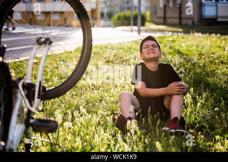 Teenage boy There is a knee injury, as the bike falls while riding. Kid hurt his leg after falling off his bicycle Stock Photo