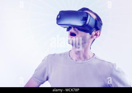 Caucasian man in t-shirt wearing virtual reality goggles on white background. Future technology concept. Stock Photo