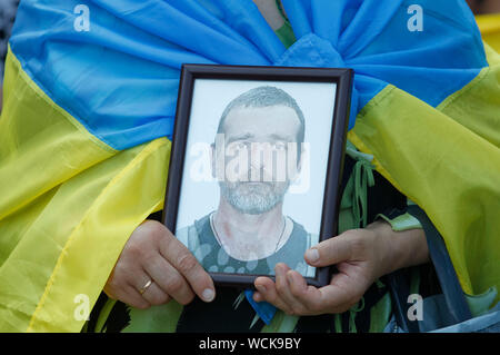 Kiev, Ukraine. 28th Aug, 2019. A relative holds a photo of the Ukrainian serviceman who was killed in fight at the Ilovaysk battle during a rally.Ukrainians mark the 5th anniversary of Ilovaysk battle on the East of Ukraine, and gathered in memory of lost the Ukrainian soldiers. According to Ukraine officials, 366 Ukrainian soldiers got lost and 158 were missing during heavy fighting between Ukrainian government forces and Russian-backed separatists at the Eastern Ukraine near of Ilovaysk city on August 2014. Credit: SOPA Images Limited/Alamy Live News Stock Photo