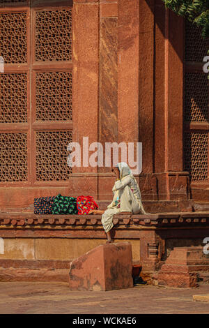 Lone woman sitting with her bags at the massive gate of Buland Darwaza, Fatehpur Sikri, Uttar Pradesh, India, Central Asia Stock Photo