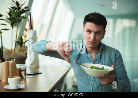 young handsome man is not satisfied with the salad showing dislike sign feeling upset . Stock Photo