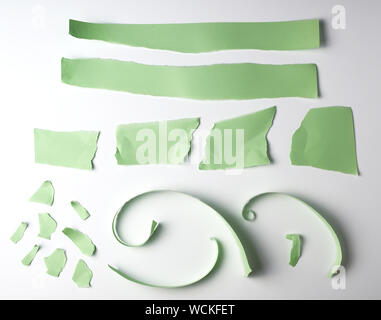 various torn strips of green paper on a white background, flat lay Stock Photo