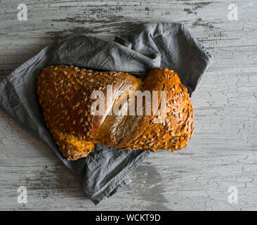 Whole wheat bread baked at home, bio ingredients, sprinkled with sunflower seeds, on natural colored rustic background. Top view, horizontal image