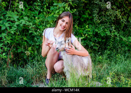 Treating animals at farm. United with nature. Animals law. Girl and goat green grass. Farm and farming concept. Village animals. Protect animals. Woman play cute goat. Veterinarian occupation. Stock Photo
