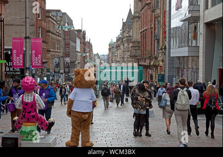 Buchanan Street Glasgow, Scotland, UK. 28th Aug, 2019. Shoppers and visitors wander along in the hazy sunshine through the pedestriansed Buchanan Street in Glasgow city centre. The Donald Dewar statue stands proudly at the top of the street, the inaugural First Minister of Scotland and an advocate of Scottish devolution, one would have to wonder what his thoughts would be regarding today's breaking news that British Prime Minister Boris Johnson has asked the Queen to suspend the UK Parliament from mid-September. Stock Photo