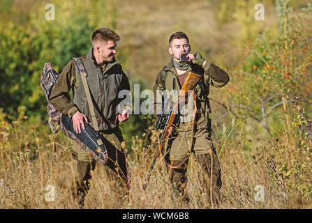 Man hunters with rifle gun. Boot camp. Hunting skills and weapon equipment. How turn hunting into hobby. Military uniform fashion. Friendship of men hunters. Hunter aiming rifle in forest. Stock Photo