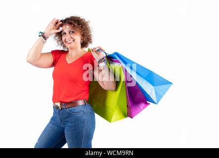 Portrait of a smiling woman wearing glasses holding shopping bags and looking at the insulated camera on a white background. Stock Photo