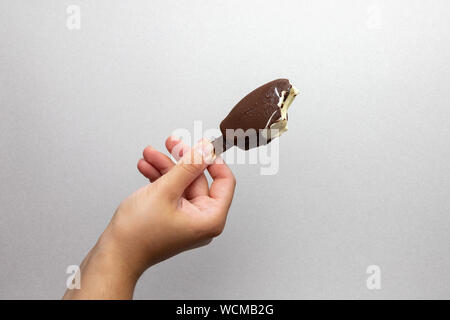Girls hand holding a mini chocolate ice cream with vanilla and almonds, sweet treat for hot summer days Stock Photo