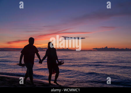 Union Pier, Michigan - A couple walks on the beach as the sun sets over Lake Michigan. Stock Photo