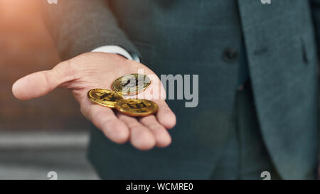 Virtual money. Cropped photo of a man holding many bitcoins in hand. Cryptocurrency Stock Photo