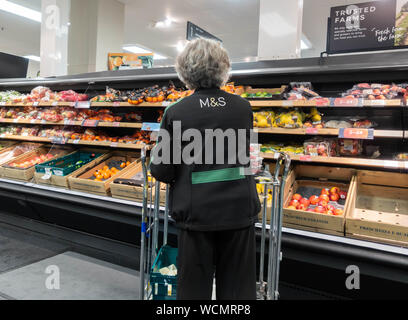 Rear view of female employee in food hall of M&S/Marks and Spencer store. UK Stock Photo