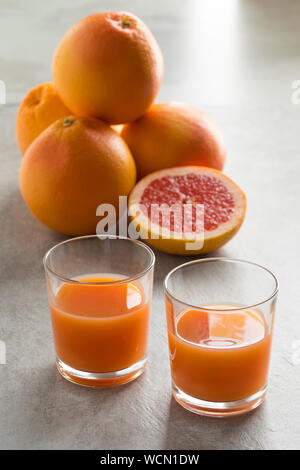 Whole and halved fresh juicy red grapefruit and glasses with juice Stock Photo