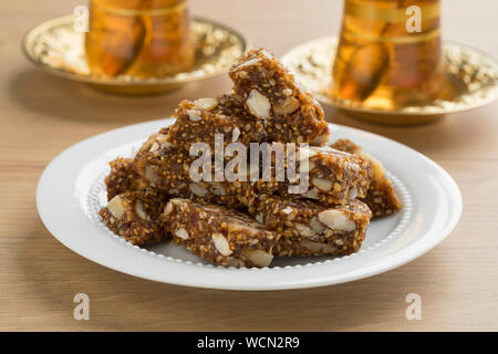 Dish with Turkish fig, fruit and nut cake pieces served with traditional tea Stock Photo