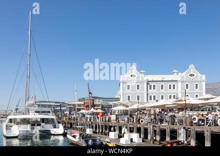 Tourists eating at  restaurants on the Wharf in the Quays, V&A Waterfront, Cape Town, South Africa overlooking the harbour and African Trading Post