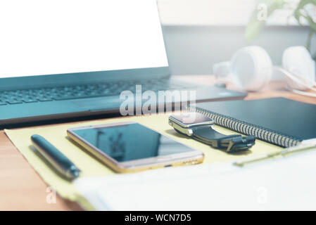 Blank laptop screen for mock up project on a business office wooden desktop. Some paperwork and a mobile with empty copy space for Editor's text. Stock Photo