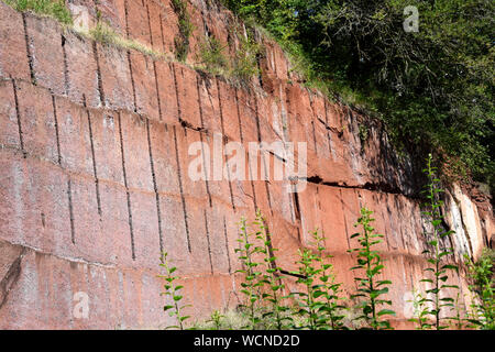Rugged Red Volcanic Tuff Rock Wall at the Michelnau Stone Pit, a Historic Site in Hesse, Germany Stock Photo