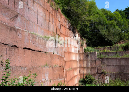 Rugged Red Volcanic Tuff Rock Wall at the Michelnau Stone Pit, a Historic Site in Hesse, Germany Stock Photo