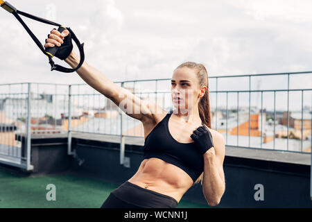 Woman doing push ups with fitness strap outdoors Stock Photo