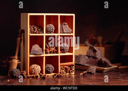 Chocolate truffles with broken pieces of chocolate and spices. Chocolate, cinnamon sticks, anise and coffee beans in wooden box. Stock Photo