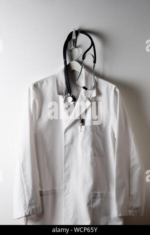 A Doctors White Lab Coat on a hanger and hook with Stethoscope. Stock Photo