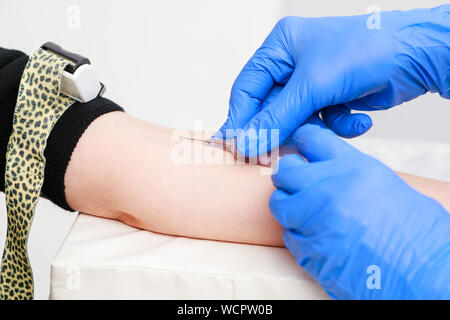 Close-up shot of doctor or nurse taking a blood sample from arm vein with a vacutainer. Venipuncture or venepuncture procedure Stock Photo