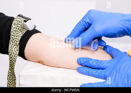 Close-up shot of doctor or nurse ready to take a blood sample from arm vein with a vacutainer. Venipuncture or venepuncture procedure Stock Photo