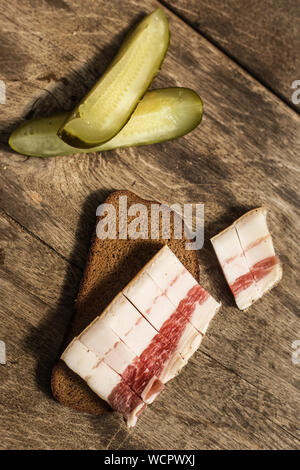 Bacon, bread and cucumber over wooden background. Russian and ukrainian traditional appetizer Stock Photo
