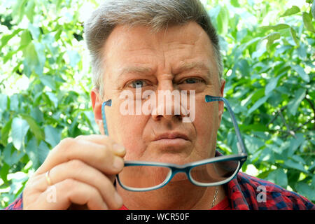 Portrait of a handsome, tired, overworked, senior man, who takes off his glasses. Stressed, sleepy, exhausted. Selective soft focus. Close-up. Stock Photo