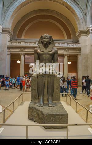 A monumental ancient Egyptian statue of a seated pharaoh at the entrance hall of the Metropolitan Museum of Art (the Met). The largest art museum. Stock Photo