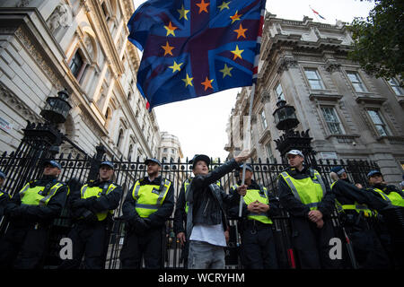 Kayden, 11, waves an EU flag and Union Jack in front of a line of police officers outside Downing Street, London, to demonstrate against Prime Minister Boris Johnson temporarily closing down the Commons from the second week of September until October 14 when there will be a Queen's Speech to open a new session of Parliament. Stock Photo