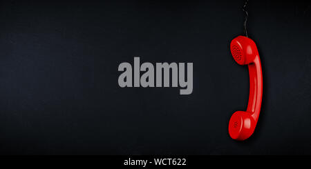 red  colored old fashioned retro phone reciever with black telephone wire on dark slate blackboard background with copy space. business communication Stock Photo