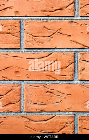 Weathered orange brick wall background. Close-up vertical photography. Decorative lining of the house. Texture with improvised borders on the surface. Stock Photo