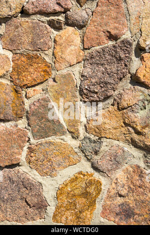 Decorative masonry from large stones background. Rough relief surface texture. Cement interlayers. Close-up detail view. Vertical photography. Stock Photo