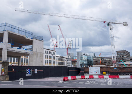 London, UK - August  2019: Huge construction yard with three big cranes working on new property development in central London Stock Photo