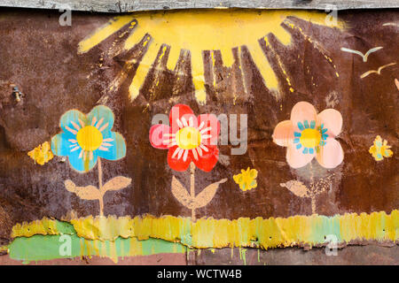Drawing flowers and the sun on the wall. The wall is made of iron, and the picture is painted with bright colors. Stock Photo