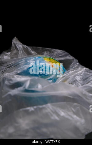 The globe covered in plastic- our irrespnsible, excessive consumerism of plastic, social advertising, world environment day concept Stock Photo