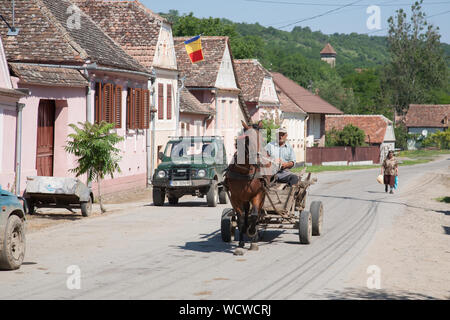 Horse and cart driven by an elderly man moving along the main street of Malancrav village, Transylvania, Romania Stock Photo